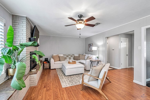 living room featuring baseboards, visible vents, a ceiling fan, wood finished floors, and a fireplace