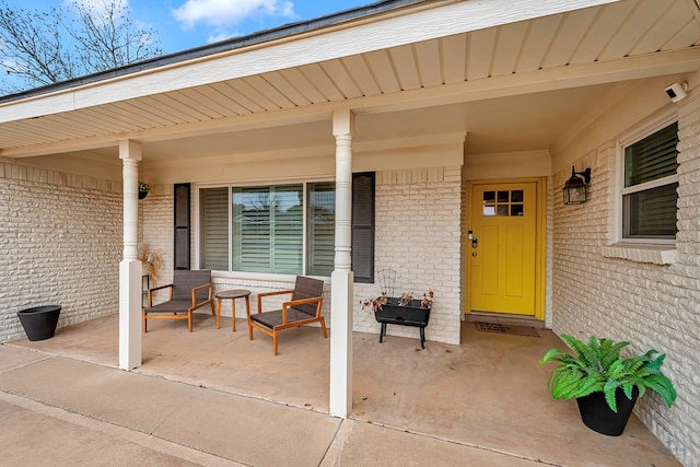 property entrance featuring a porch and brick siding