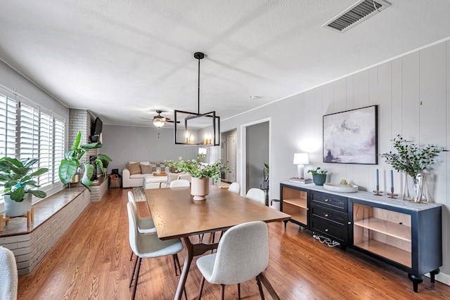 dining area with ceiling fan, light wood-style flooring, a textured ceiling, and visible vents