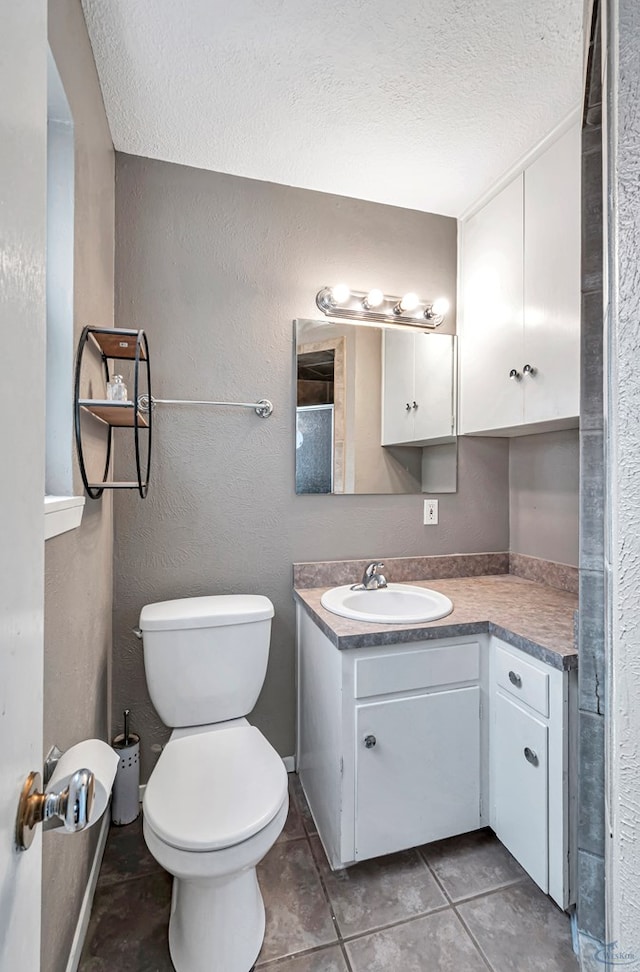 bathroom featuring a textured wall, toilet, tile patterned flooring, a textured ceiling, and vanity