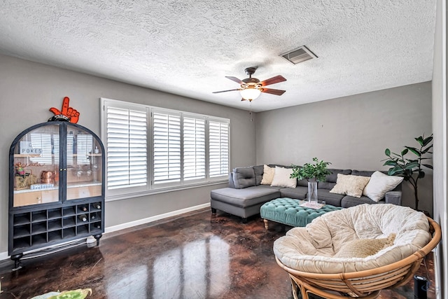 living room with ceiling fan, a textured ceiling, visible vents, baseboards, and finished concrete floors