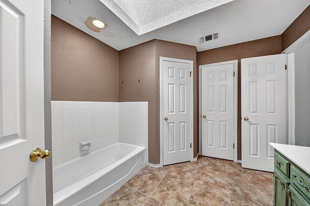 2209 Southampton Ln, Midland, TX 79705 - full bathroom with a bath, vanity, a textured wall, a textured ceiling, and tile patterned floors