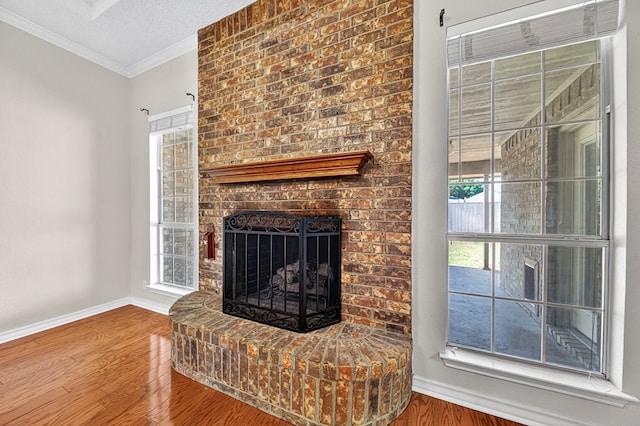 2209 Southampton Ln, Midland, TX 79705 - unfurnished living room featuring wood finished floors, crown molding, a fireplace, plenty of natural light, and a textured ceiling