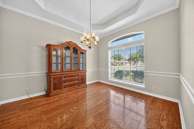 2209 Southampton Ln, Midland, TX 79705 - empty room featuring a chandelier, a textured ceiling, wood finished floors, a tray ceiling, and ornamental molding