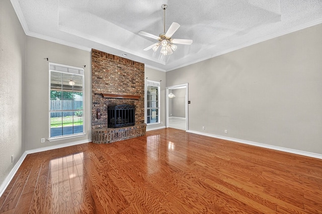 2209 Southampton Ln, Midland, TX 79705 - unfurnished living room with a textured ceiling, wood finished floors, a ceiling fan, a brick fireplace, and a raised ceiling