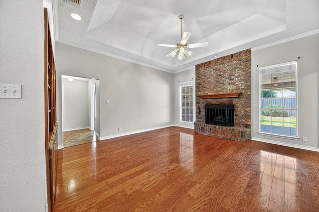 2209 Southampton Ln, Midland, TX 79705 - unfurnished living room with a raised ceiling, a ceiling fan, wood finished floors, a brick fireplace, and ornamental molding