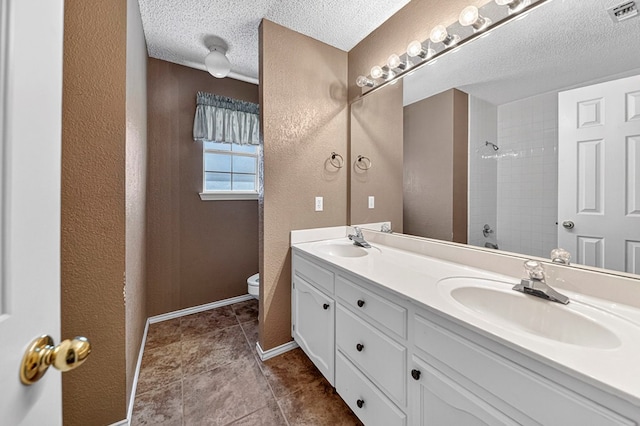 2209 Southampton Ln, Midland, TX 79705 - bathroom with double vanity, a textured ceiling, a tile shower, tile patterned flooring, and a textured wall