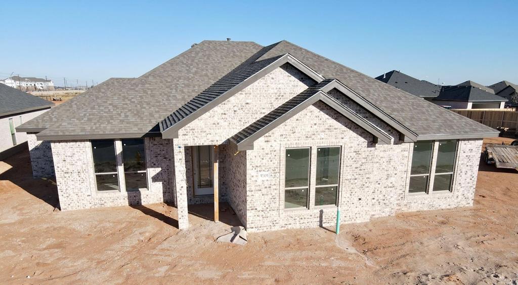 rear view of property featuring roof with shingles and brick siding
