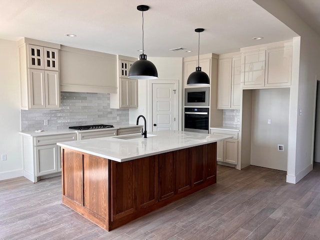 kitchen featuring a sink, black oven, stainless steel microwave, light countertops, and tasteful backsplash