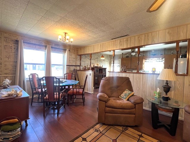 3702 Dalton Dr, Snyder, TX 79549 - dining space featuring ceiling fan with notable chandelier, wood finished floors, wood walls, and visible vents