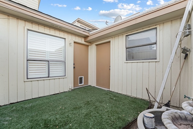 view of exterior entry with a yard