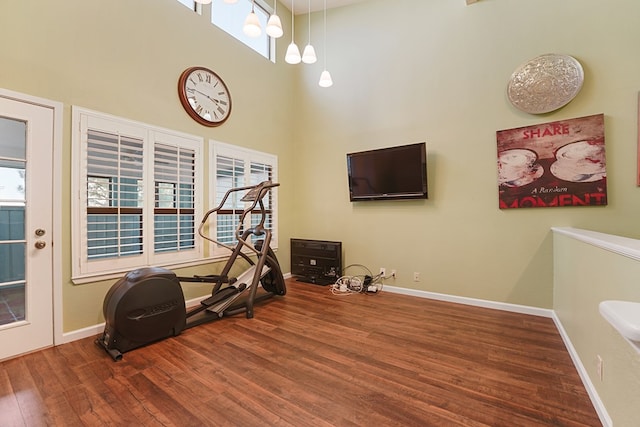 exercise area with a towering ceiling and hardwood / wood-style floors