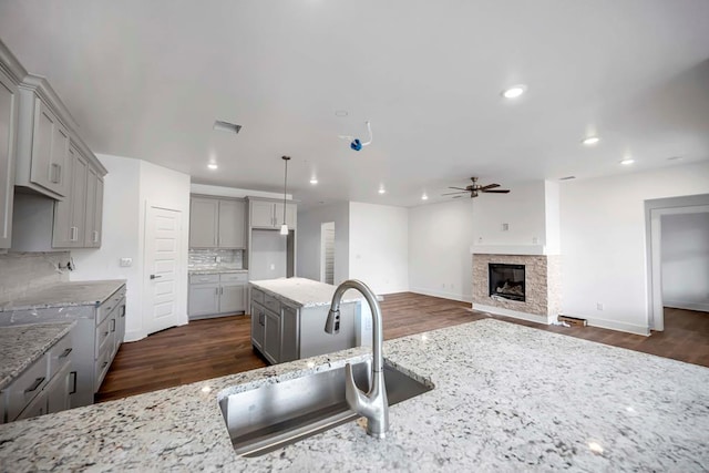 8643 Santa Isabella, Odessa, TX 79765 - kitchen with gray cabinets, a sink, a ceiling fan, light stone counters, and decorative backsplash