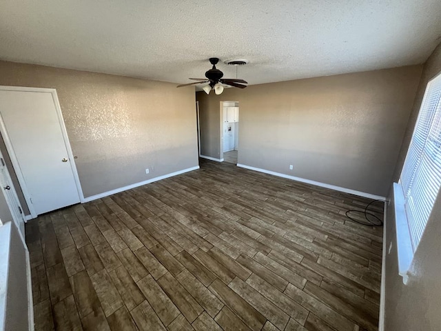 spare room featuring dark hardwood / wood-style floors, ceiling fan, and a textured ceiling