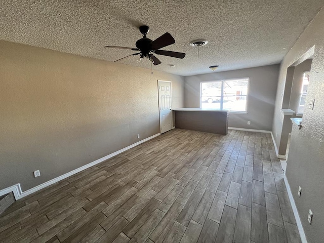 unfurnished bedroom with hardwood / wood-style floors, a textured ceiling, and ceiling fan