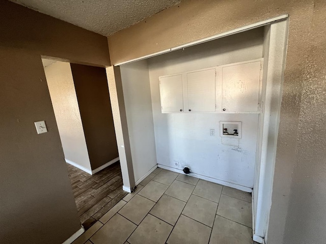 laundry area with electric dryer hookup, cabinets, hookup for a washing machine, a textured ceiling, and light hardwood / wood-style floors