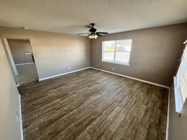 empty room with ceiling fan, dark wood-type flooring, and a textured ceiling