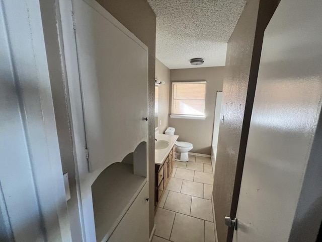 bathroom featuring tile patterned floors, vanity, toilet, and a textured ceiling