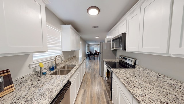 kitchen featuring stainless steel appliances, visible vents, light wood-style flooring, white cabinets, and a sink