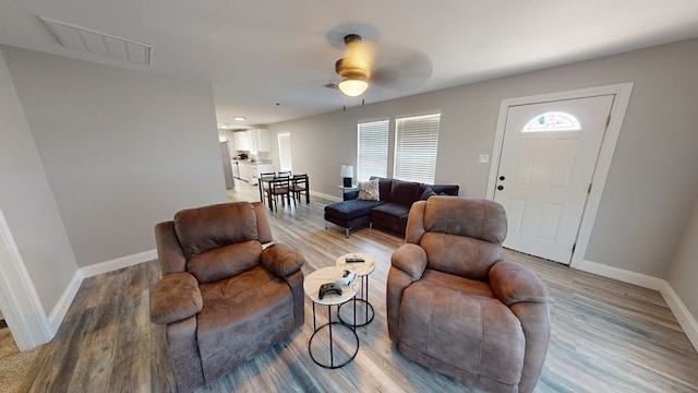 living room with a ceiling fan, baseboards, and wood finished floors