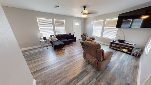 living room featuring a healthy amount of sunlight, visible vents, baseboards, and wood finished floors