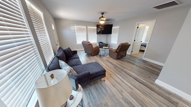 living room featuring baseboards, visible vents, ceiling fan, and wood finished floors