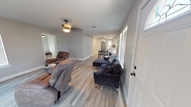 living room featuring baseboards, a wealth of natural light, visible vents, and light wood-style floors