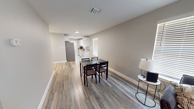 dining area featuring light wood-style floors, baseboards, and visible vents