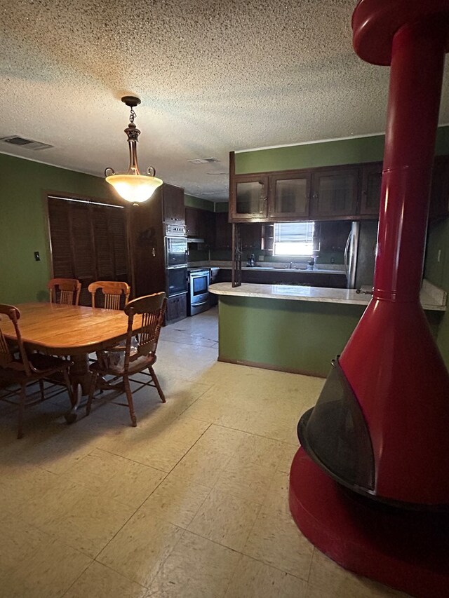 kitchen featuring decorative light fixtures, dark brown cabinets, kitchen peninsula, and a textured ceiling