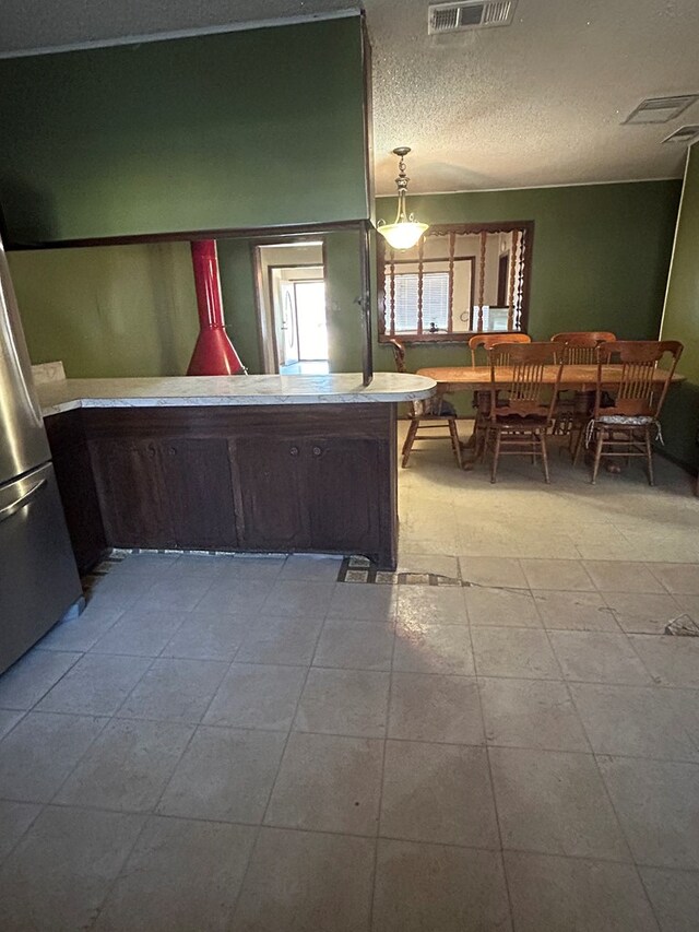 unfurnished bedroom featuring stainless steel refrigerator, light tile patterned floors, and a textured ceiling