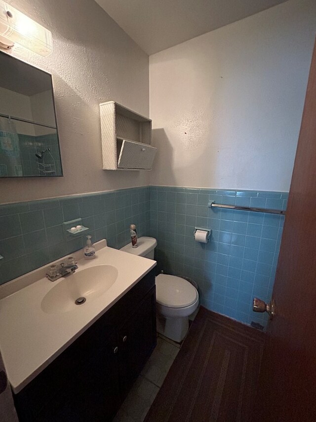 bathroom featuring tile patterned floors, vanity, tile walls, and toilet