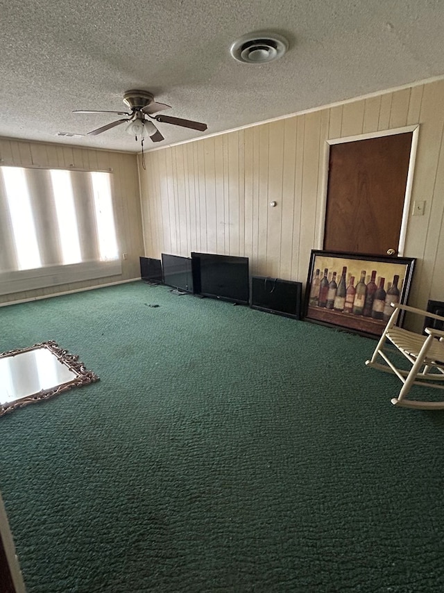 unfurnished room with carpet flooring, a textured ceiling, and wooden walls