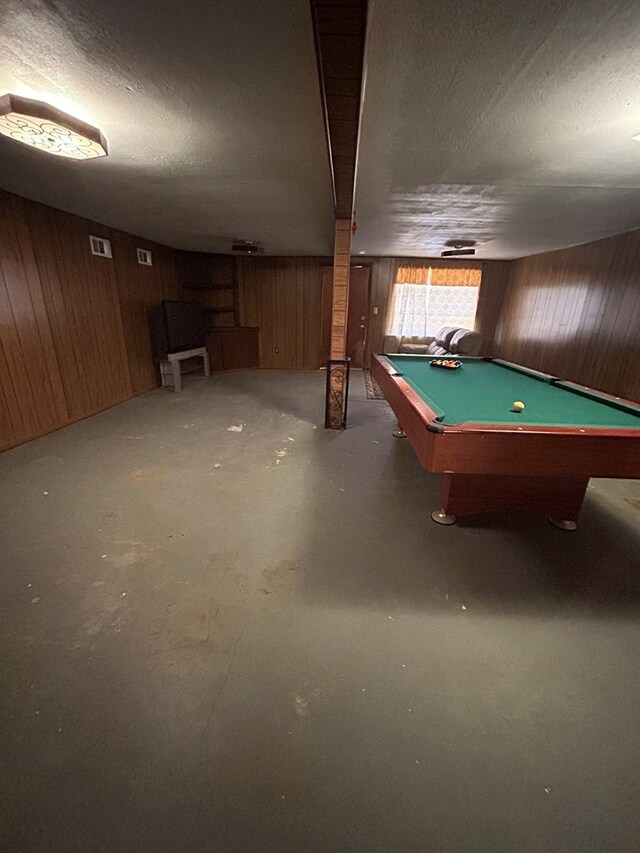 game room featuring wood walls, concrete floors, a textured ceiling, and billiards