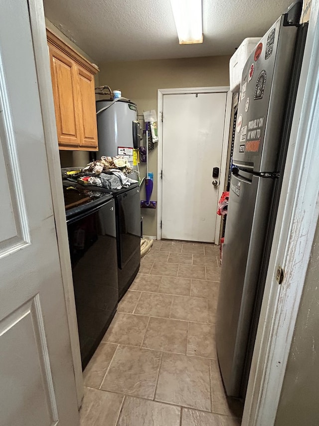 laundry room featuring washer and clothes dryer, a textured ceiling, and water heater