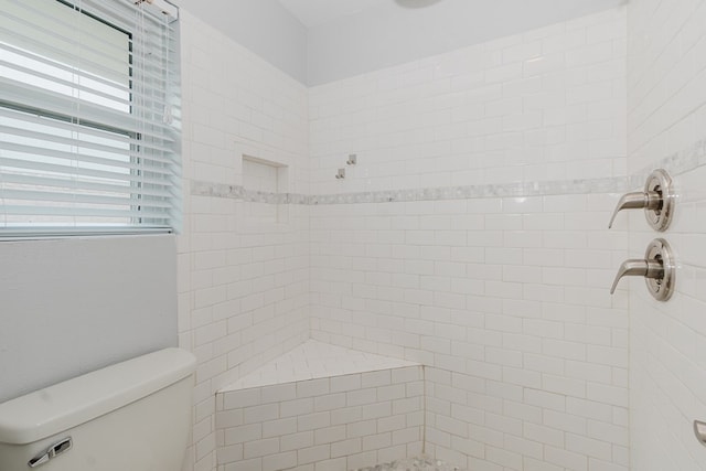 bathroom with toilet and a tile shower