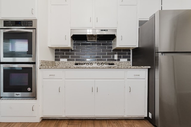 kitchen featuring tasteful backsplash, exhaust hood, white cabinetry, and stainless steel appliances