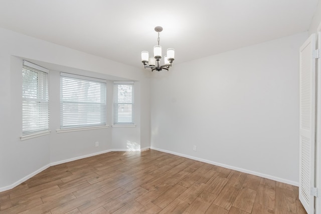 empty room with light hardwood / wood-style flooring and a notable chandelier