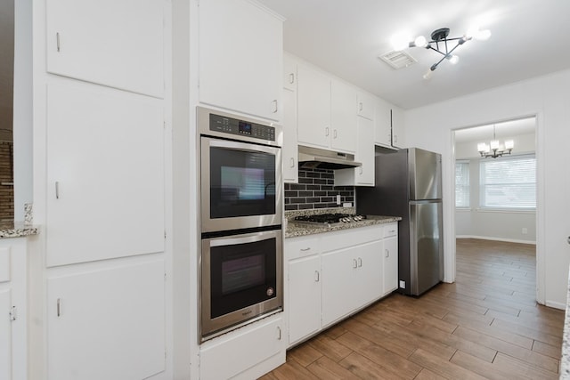 kitchen with white cabinets, decorative backsplash, a chandelier, and appliances with stainless steel finishes