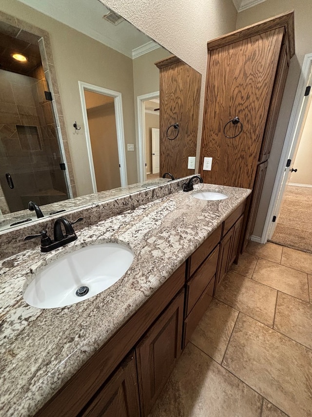 bathroom with visible vents, a sink, ornamental molding, and a shower stall