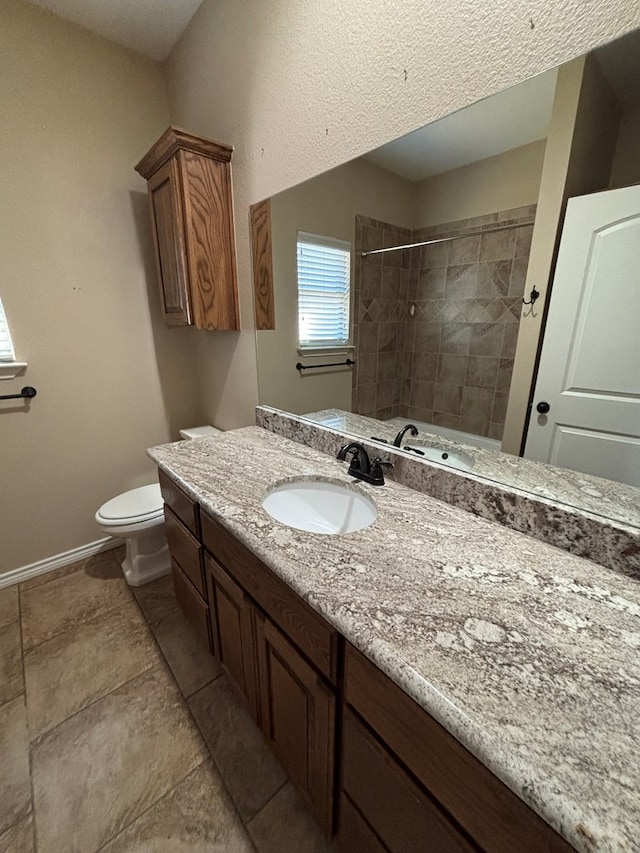 bathroom featuring vanity, baseboards, a tile shower, and toilet