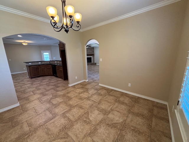 unfurnished dining area with crown molding, a notable chandelier, arched walkways, stone finish floor, and baseboards