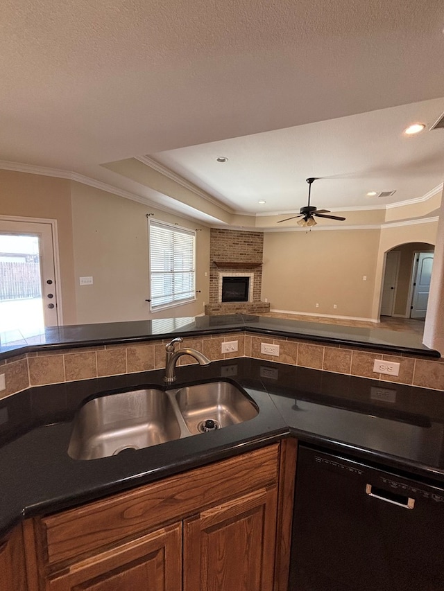 kitchen with ornamental molding, dark countertops, open floor plan, a sink, and dishwasher