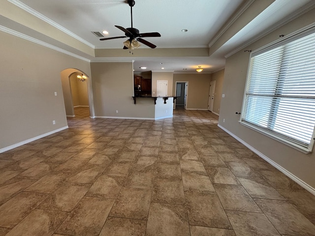 unfurnished living room with a ceiling fan, a tray ceiling, baseboards, and arched walkways