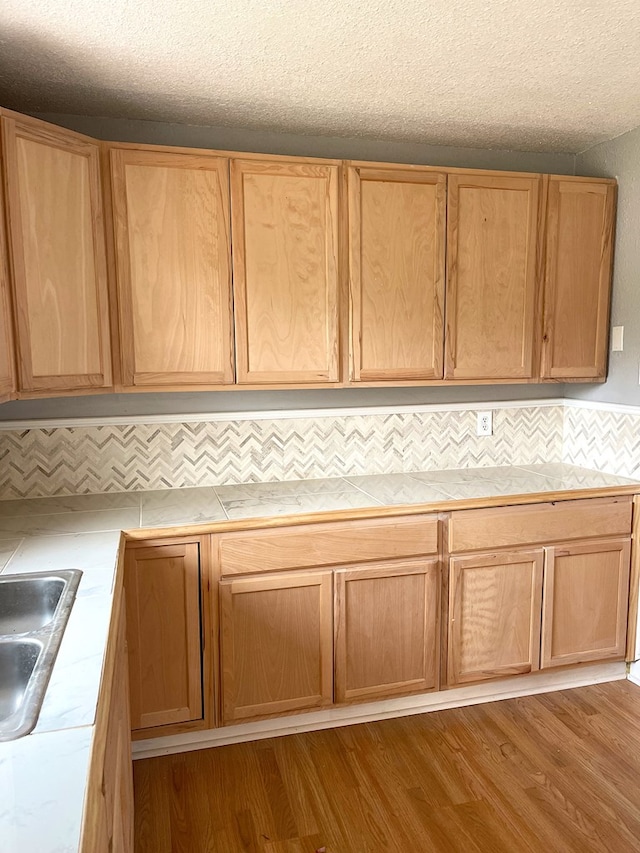 kitchen featuring tile counters, a sink, dark wood finished floors, and tasteful backsplash
