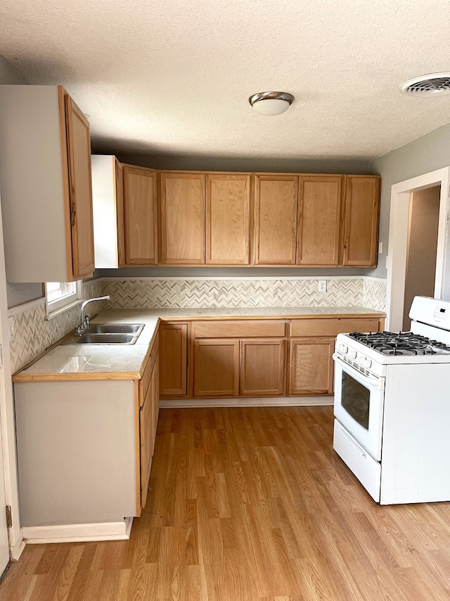 kitchen featuring visible vents, a sink, light countertops, white gas range oven, and backsplash
