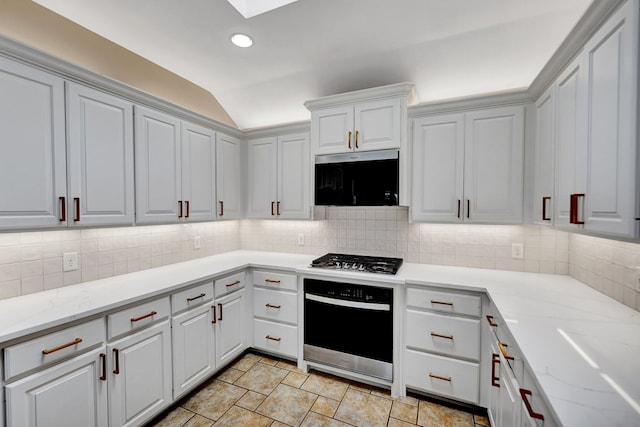 kitchen with wall oven, stainless steel gas stovetop, a skylight, lofted ceiling, and backsplash