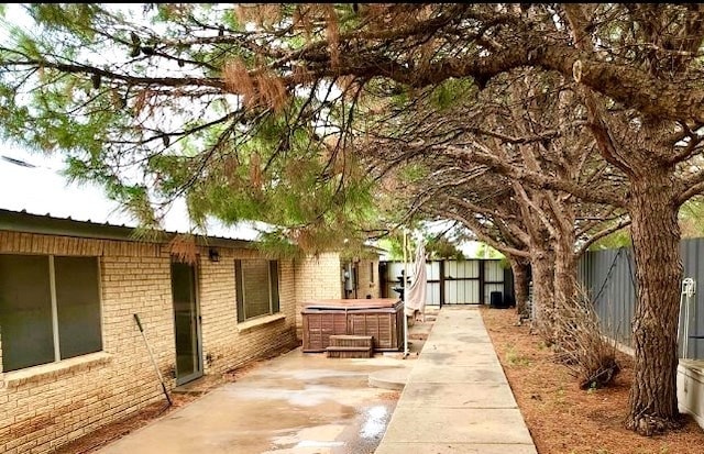 view of side of home featuring a patio area and a hot tub