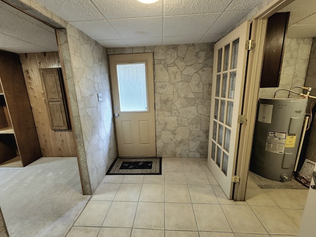 doorway to outside featuring a paneled ceiling, light tile patterned flooring, and water heater