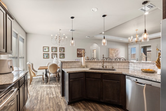 kitchen featuring sink, dark hardwood / wood-style flooring, backsplash, pendant lighting, and appliances with stainless steel finishes