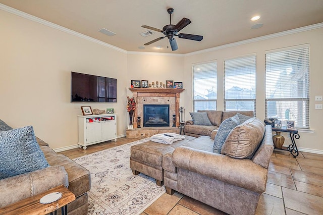 tiled living room featuring ceiling fan, ornamental molding, and a tiled fireplace